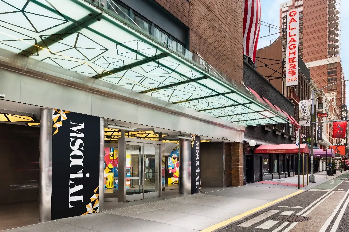 Entrance of M Social Times Square showcasing modern architecture and vibrant colors, positioned near iconic New York establishments.
