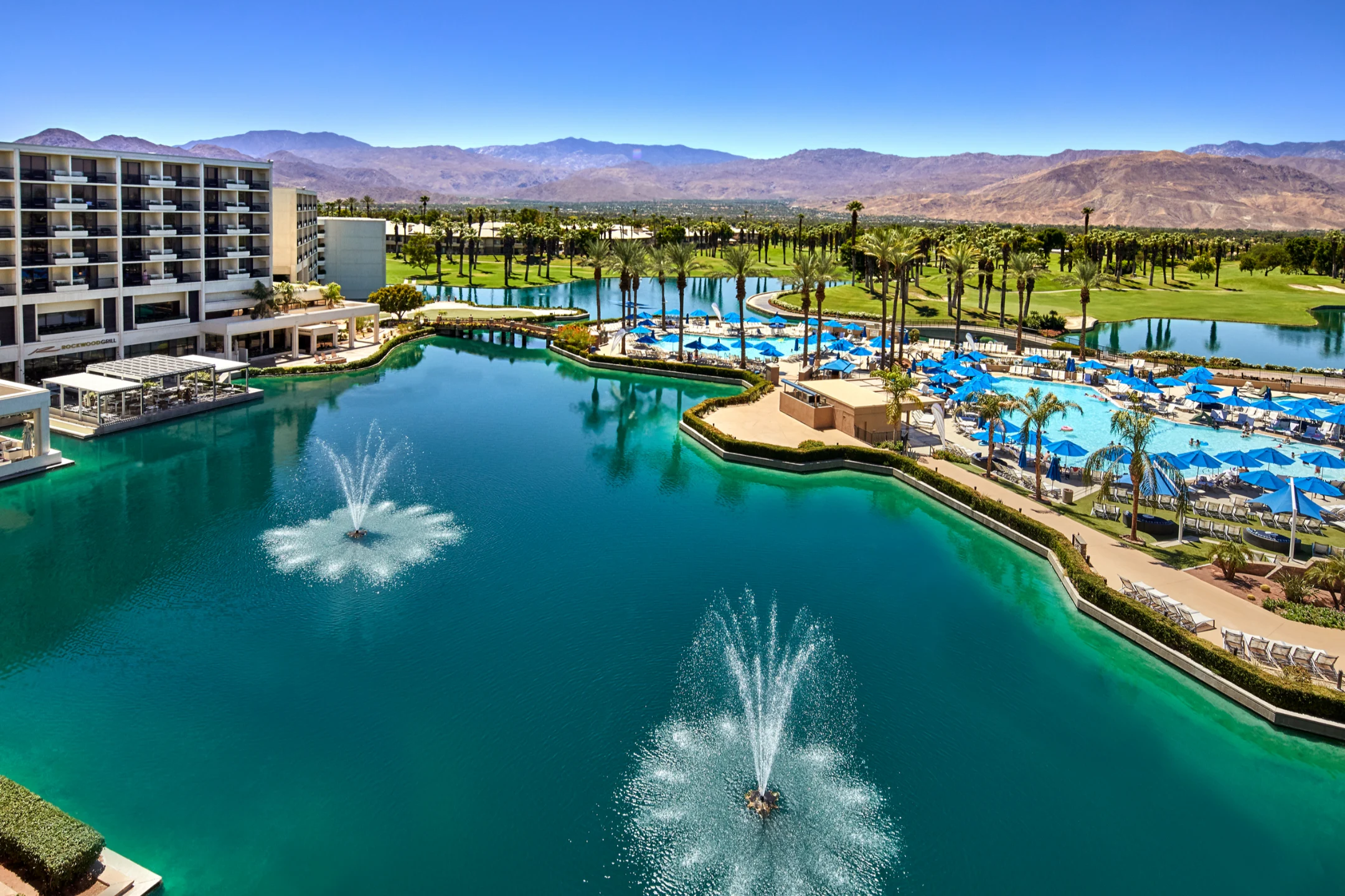 JW Marriott Desert Springs Resort features a poolside view with fountains, palm trees, and mountains in the background.