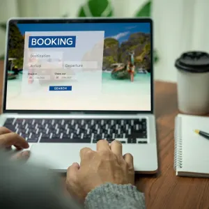 User interacting with a laptop booking system for luxury multi-destination vacation planning.