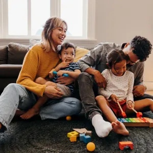 A happy family plays together on the floor, engaging with toys and enjoying quality time during a cozy afternoon.