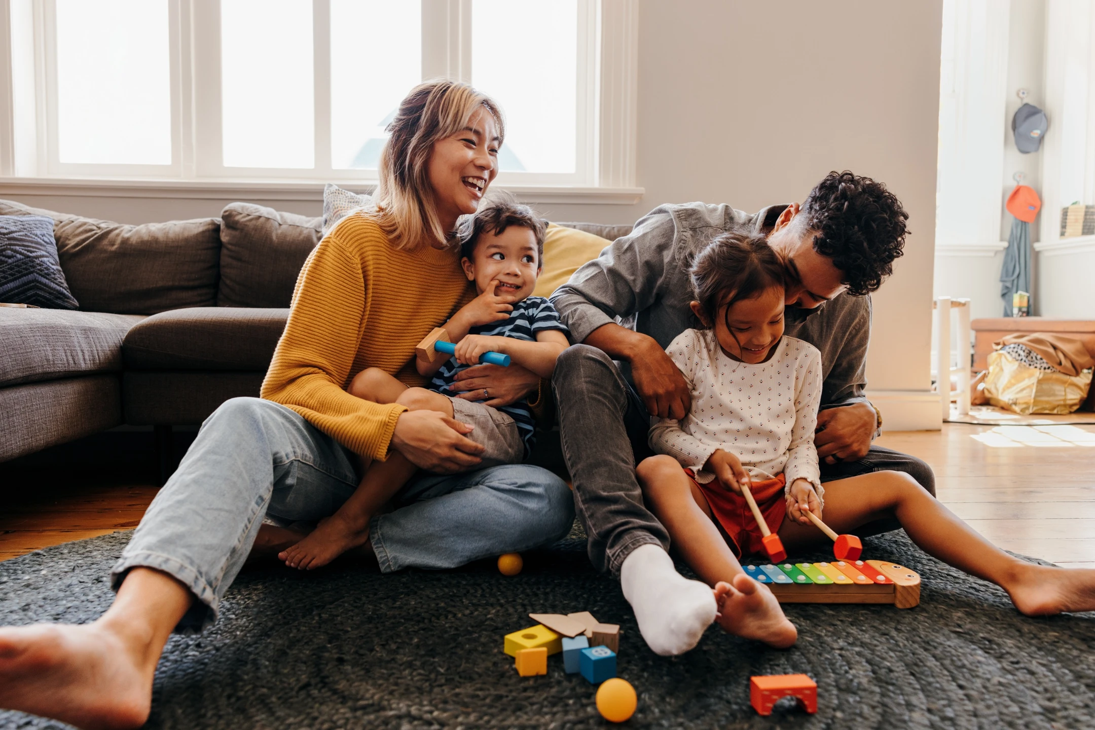 A happy family plays together on the floor, engaging with toys and enjoying quality time during a cozy afternoon.