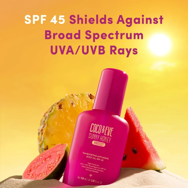 Coco & Eve Sunny Honey body oil with SPF 45, surrounded by tropical fruits against a bright background.