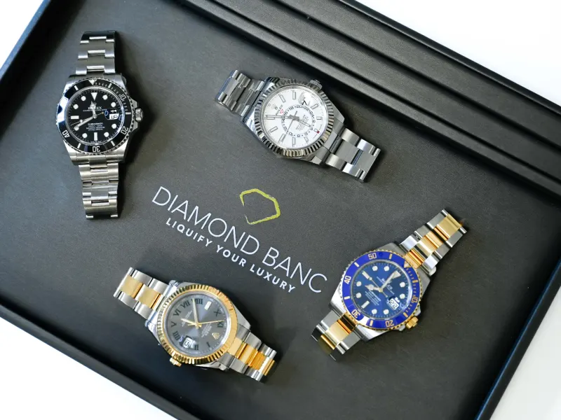 Four luxury Rolex watches displayed in a black box featuring the Diamond Banc logo, highlighting luxury timepieces.