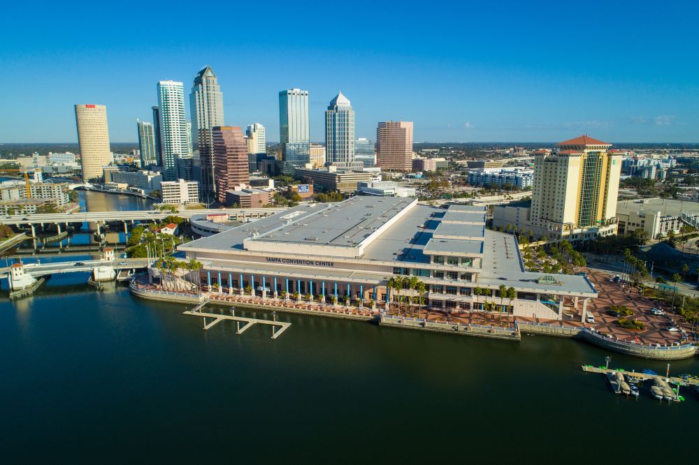 Aerial view of the Tampa Convention Center with the city skyline and water in the foreground.