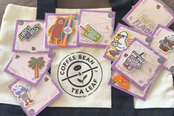 Colorful embroidered patches featuring coffee and tea themes on a tote bag from The Coffee Bean & Tea Leaf.