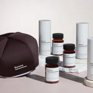 Bomme hair wellness products including scalp toner and dietary supplements displayed on a neutral surface.