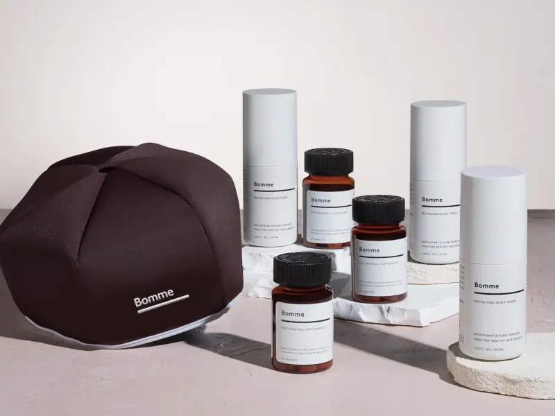 Bomme hair wellness products including scalp toner and dietary supplements displayed on a neutral surface.