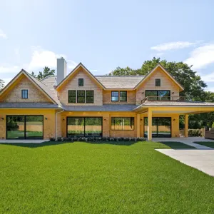 Luxurious East Hampton new build featuring large windows, a spacious yard, and a covered patio near the pool.
