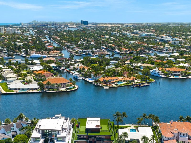 Aerial view of waterfront estates and canals in South Florida, showcasing luxury homes and lush waterfront landscaping.