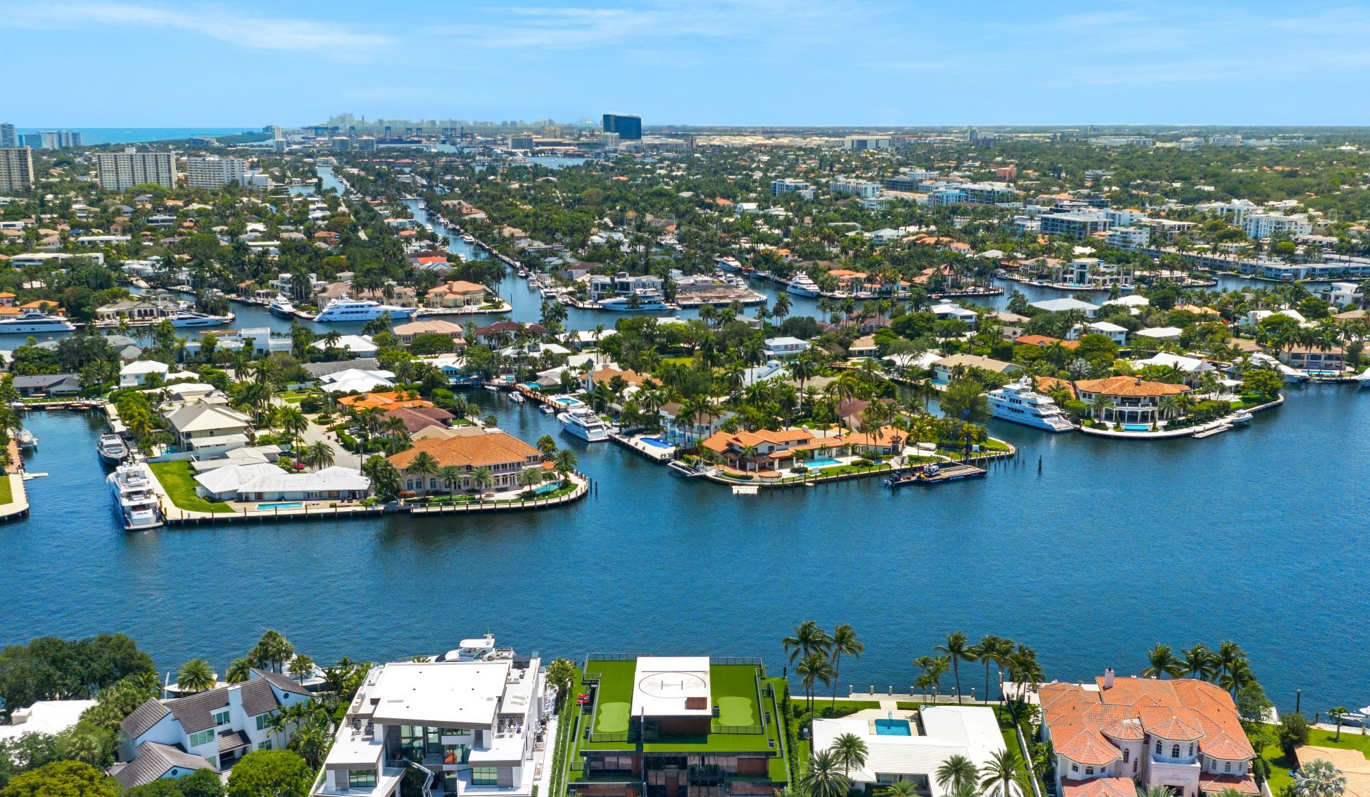 Aerial view of waterfront estates and canals in South Florida, showcasing luxury homes and lush waterfront landscaping.