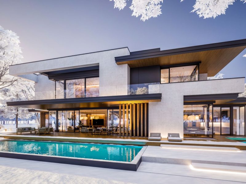Modern luxury home featuring sleek architecture, a pool, and large glass windows, surrounded by a winter landscape.