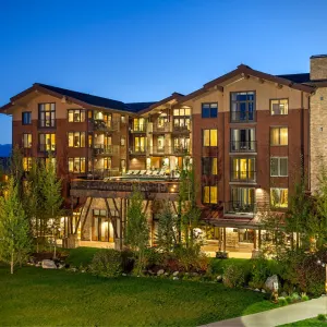 Jackson Hole luxury hotel exterior featuring modern architecture and landscaped grounds under a twilight sky.