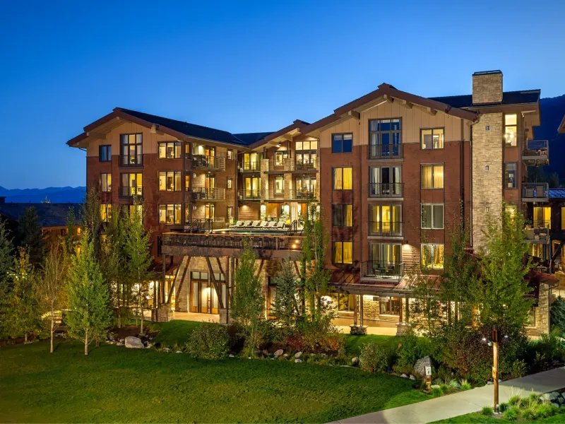 Jackson Hole luxury hotel exterior featuring modern architecture and landscaped grounds under a twilight sky.