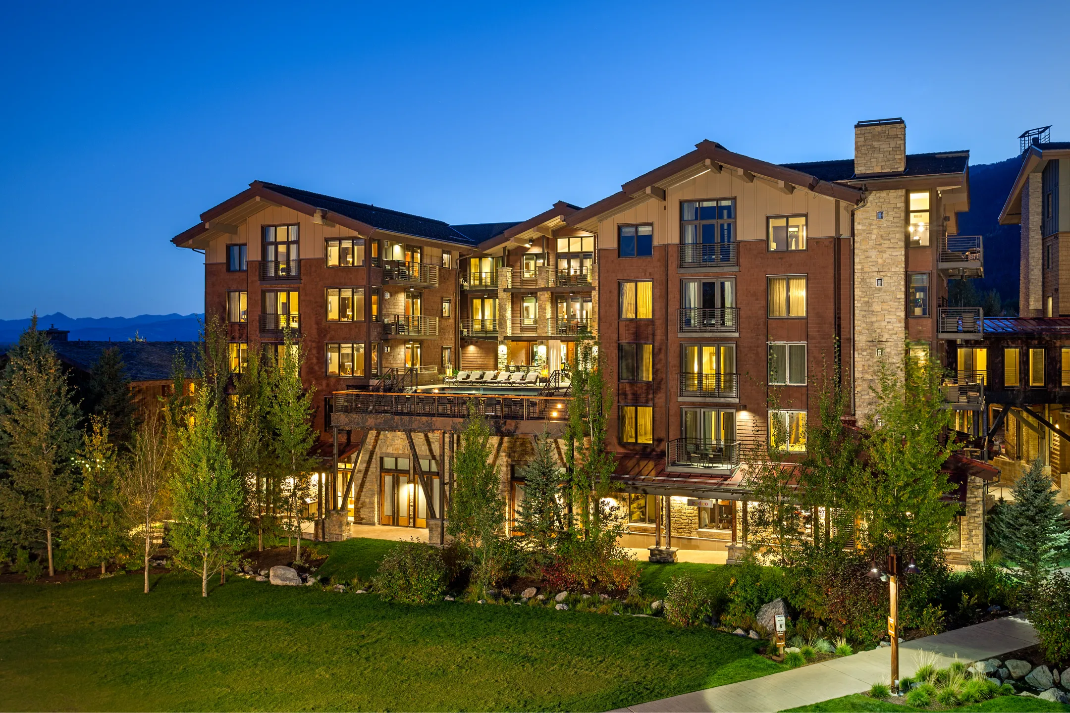 Jackson Hole luxury hotel exterior featuring modern architecture and landscaped grounds under a twilight sky.