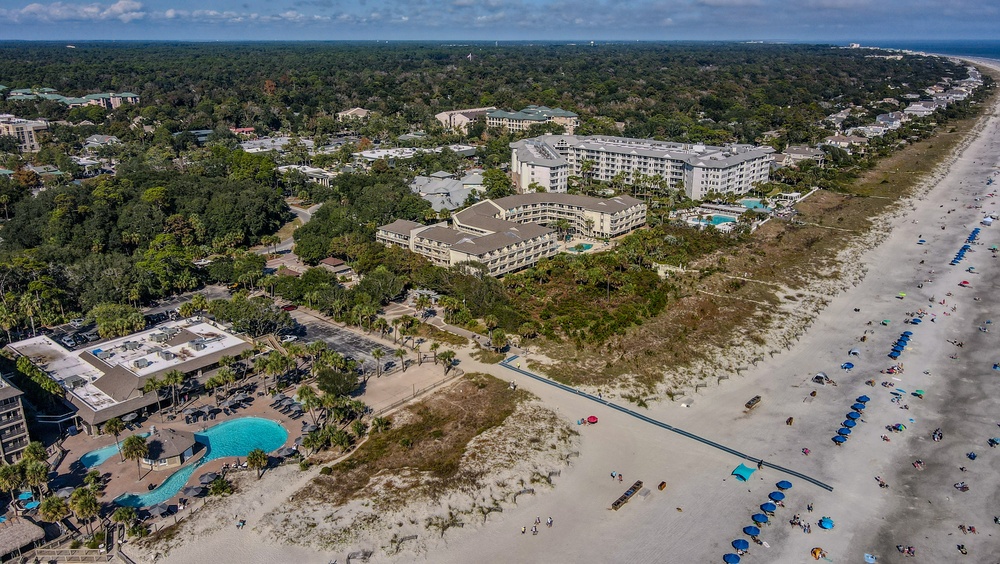 Aerial view of Hilton Head Island showcasing beach homes, pools, and umbrellas lining the shore.