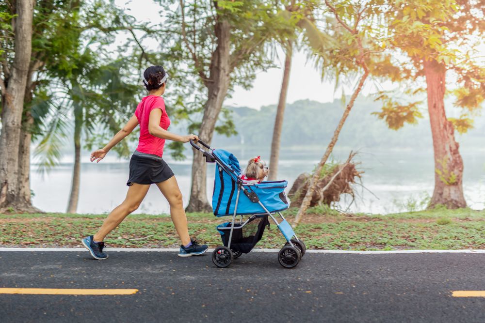 Person jogging beside a pet stroller in a park, ideal for discussing features to consider when buying a pet stroller.