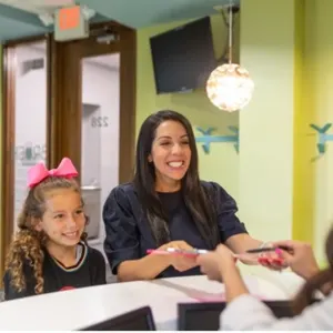 Smiling mother and daughter at a dental office reception, engaging with staff and discussing dental care.
