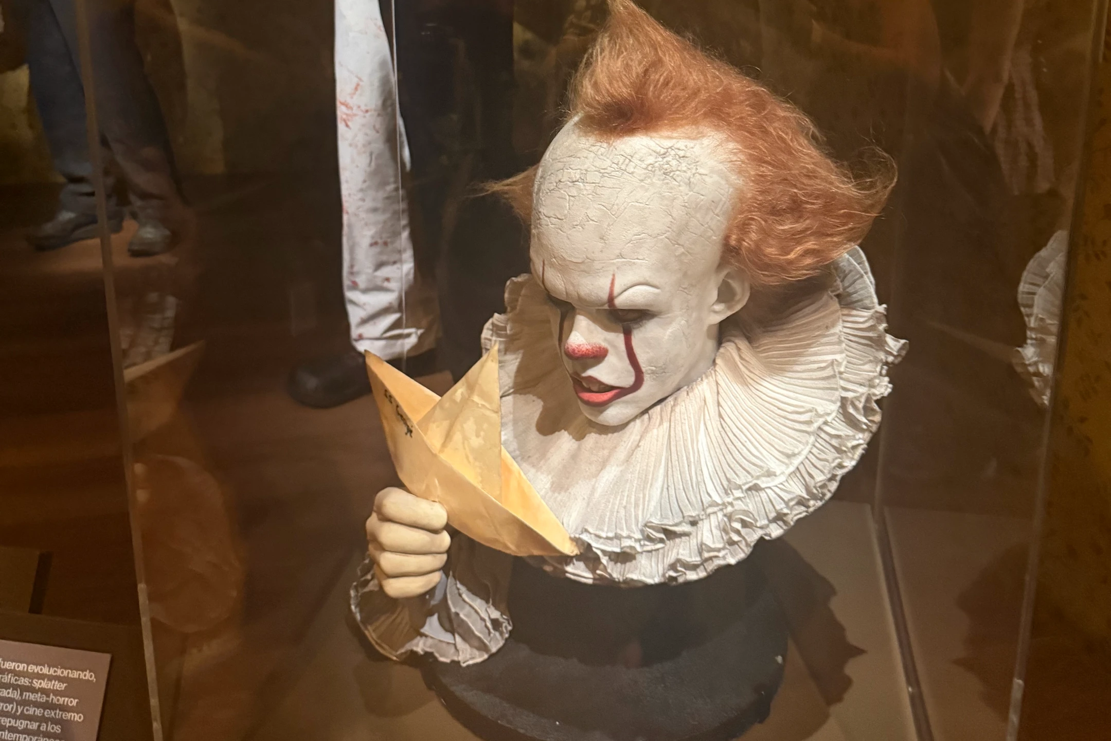 Clown figure holding a paper boat, featured in a horror exhibition at the Academy Museum.