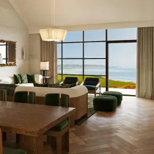 Modern great room with a view of the ocean, featuring a wooden dining table, cozy seating, and stylish decor.