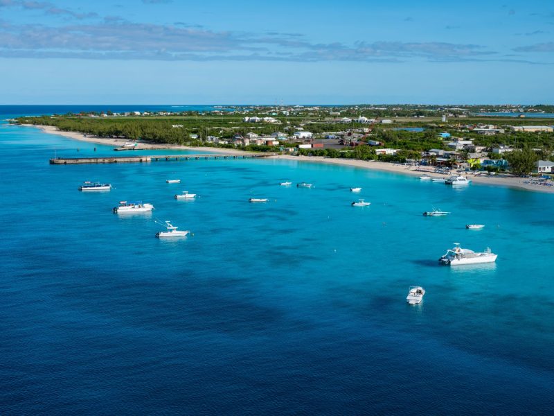 Aerial view of turquoise waters dotted with boats near a tropical shoreline in Turks and Caicos.