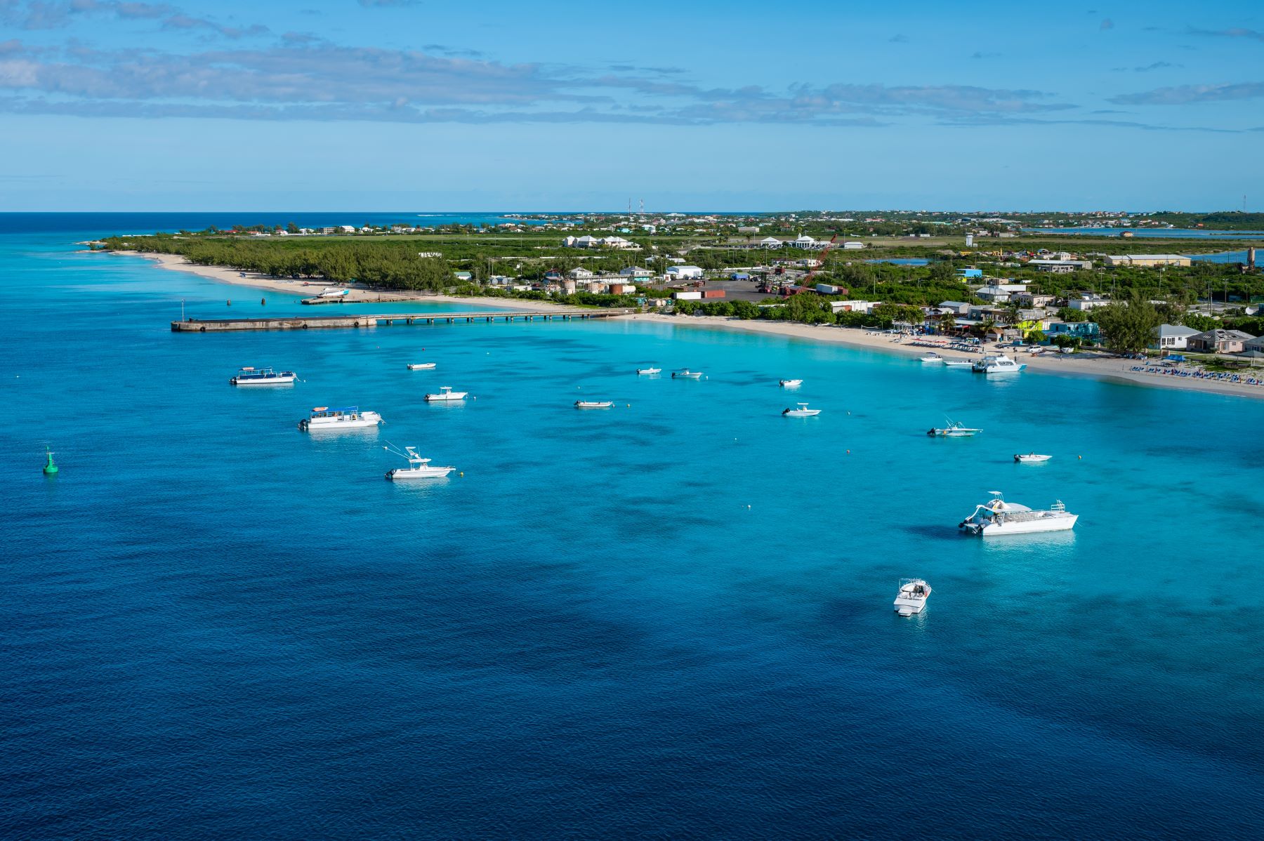 Aerial view of turquoise waters dotted with boats near a tropical shoreline in Turks and Caicos.