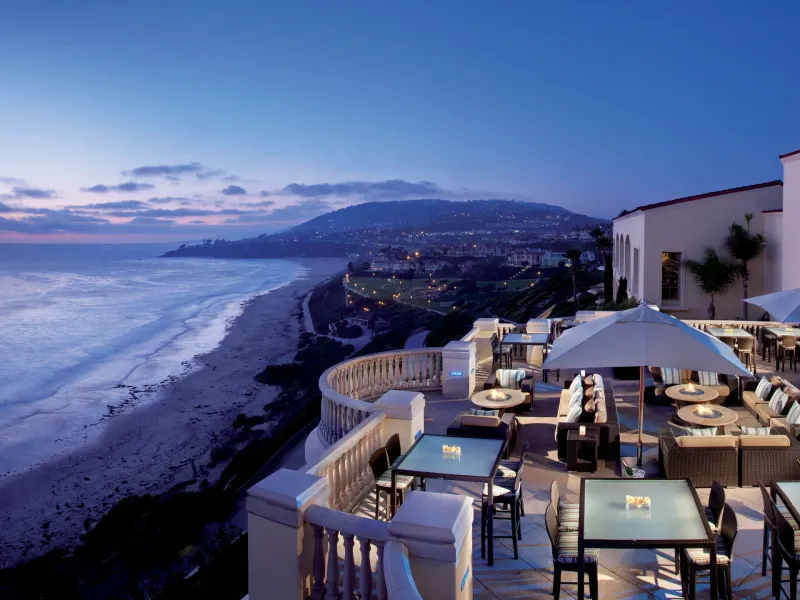 Views of the ocean from the terrace of The Ritz-Carlton, Laguna Niguel, with seating and glowing lights at dusk.