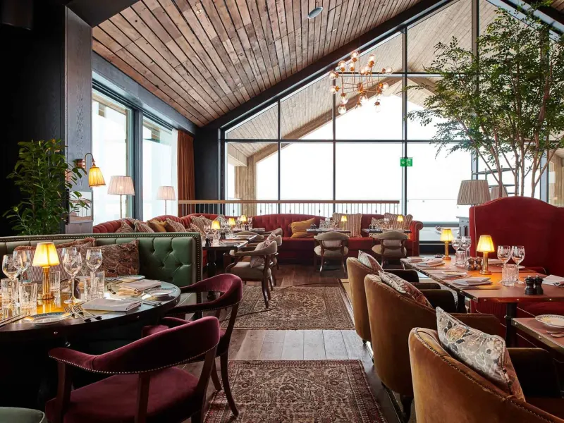 Elegant restaurant interior at a Norwegian resort, featuring stylish furnishings, panoramic windows, and a cozy atmosphere.