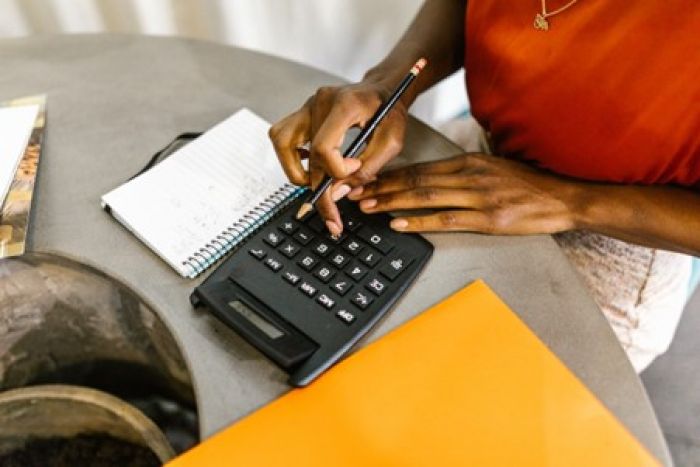 a person using a calculator for budgeting before buying